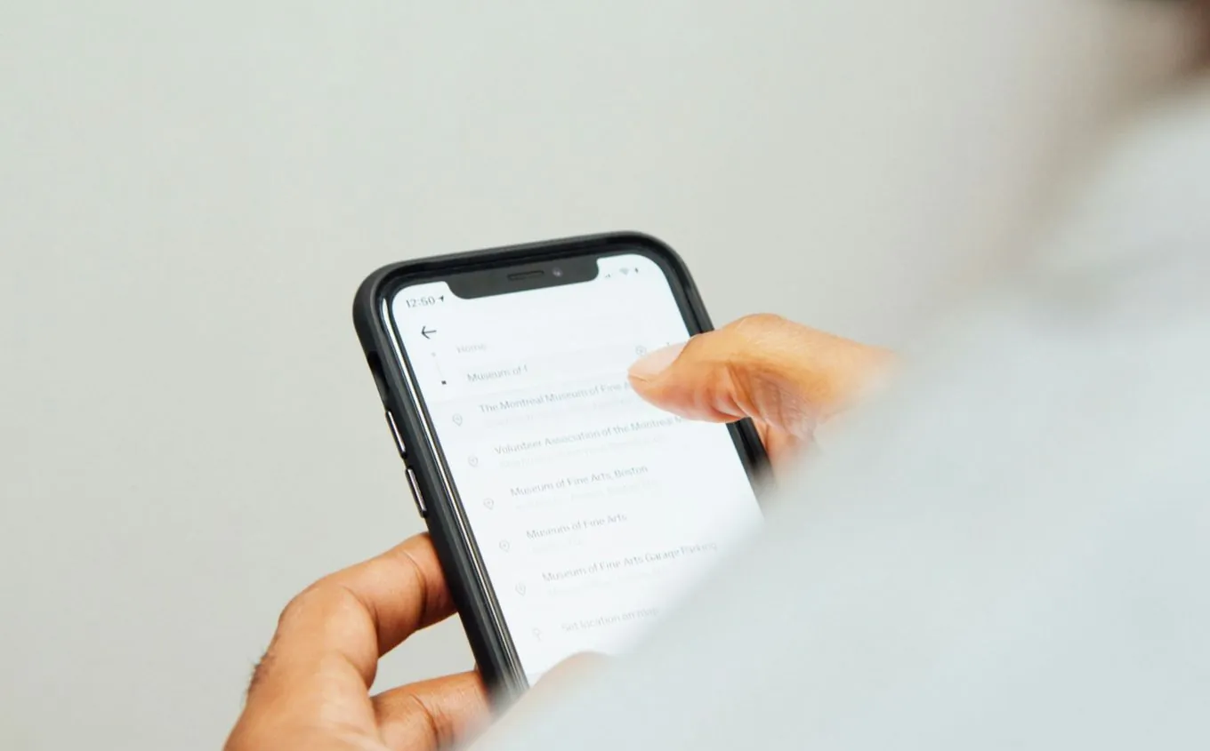A hand scrolling through a list of search results on a phone